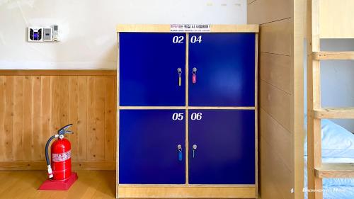 a blue locker in a room with a fire extinguisher at Backpacker's Home in Seogwipo