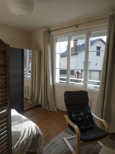 ein Schlafzimmer mit einem Bett, einem Stuhl und einem Fenster in der Unterkunft Le Ténor - Appartement - Parking gratuit in Orléans