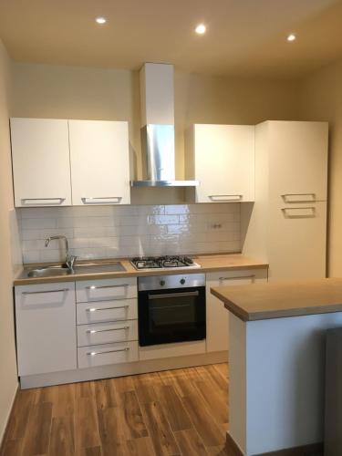 uma cozinha com armários brancos e um forno com placa de fogão em Casa Maka' em Olbia