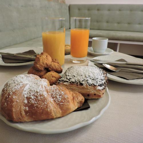 a plate of pastries on a table with two glasses of orange juice at Boutique Hotel Masolino in Panicale