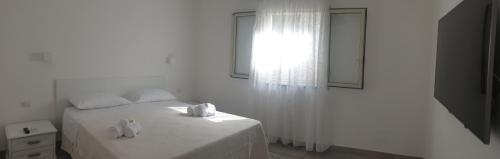 graziosa villetta III في لامبيدوسا: غرفة نوم بيضاء بها سرير ونافذة