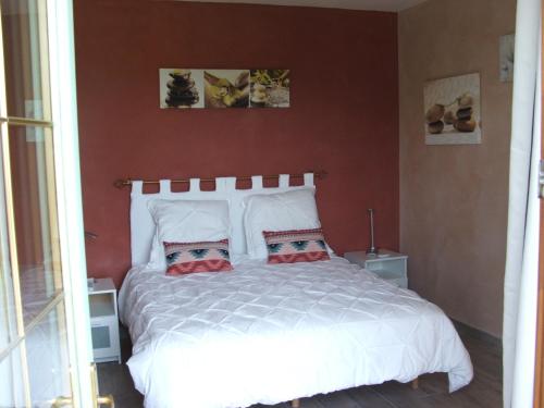 a bedroom with a white bed with two pillows at La Zénitude in Les Lèches