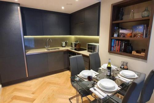 a kitchen with a dining table and a kitchen with black cabinets at Luxury One Bedroom Apartment Within the City Walls in York