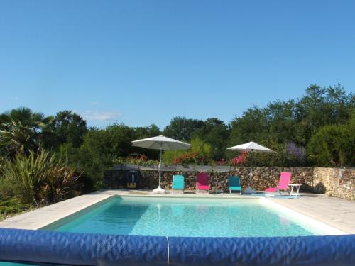 une piscine avec chaises et parasols dans une cour dans l'établissement La Zénitude, à Les Lèches