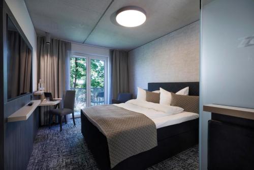 a hotel room with a bed and a desk and a window at Hotel Zeitgeist in Warburg