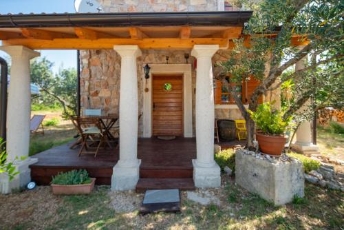 a house with a wooden porch with a table at Villa Flaveico in Pašman