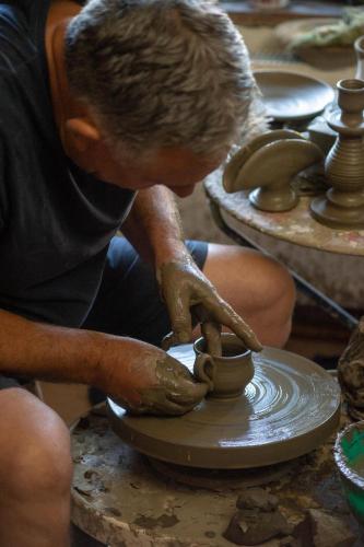 a man making a pot on a pottery wheel at Conacul Paloși in Horezu