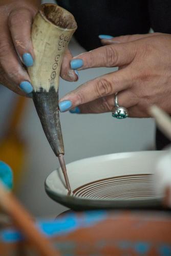 a person holding a knife over a plate at Conacul Paloși in Horezu