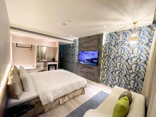 a bedroom with a bed and a tv and a couch at Fifth Avenue Motel in Taichung