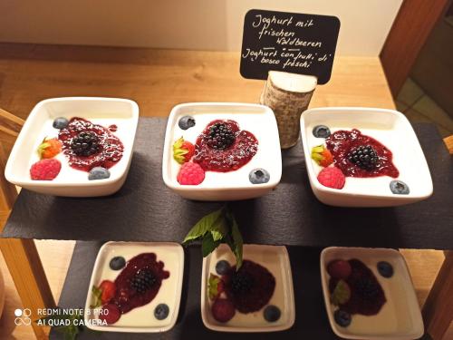 a table with four dishes of fruit and berries at Pension Ederhof in San Giacomo