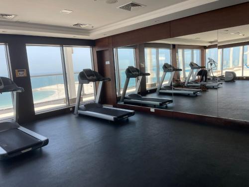 a gym with a row of treadmills and mirrors at Breathtaking Studio Apartment in Marjan Island in Ras al Khaimah