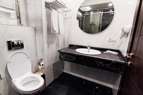 a bathroom with a toilet and a sink and a mirror at East Palace Hotel in Almaty