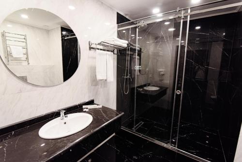 a black and white bathroom with a sink and a shower at East Palace Hotel in Almaty