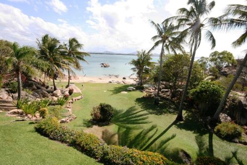 a view of a beach with palm trees and the ocean at Whitsunday Sands Resort in Bowen