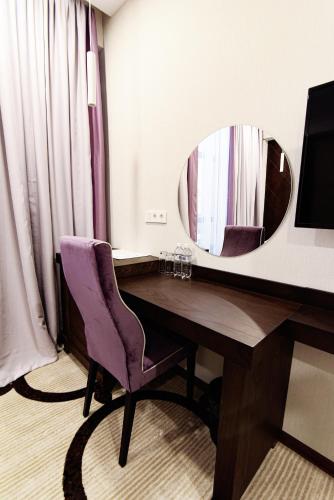 a room with a desk with a mirror and a chair at East Palace Hotel in Almaty