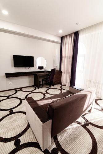 a living room with a couch and a flat screen tv at East Palace Hotel in Almaty
