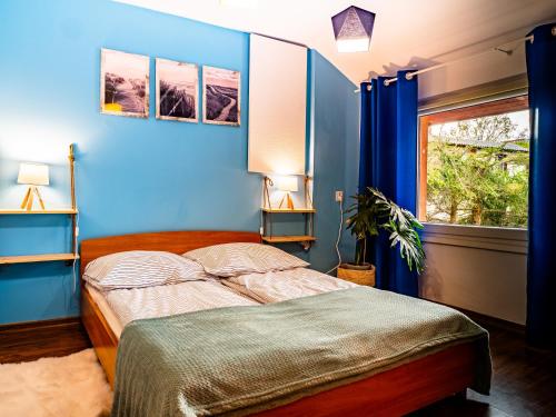 a bedroom with a bed with blue walls and a window at Domek InoSasino z basenem i sauną in Sasino