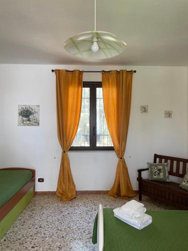 Schlafzimmer mit orangefarbenen Vorhängen und Fenster in der Unterkunft La casetta degli ulivi con piscina in Menfi
