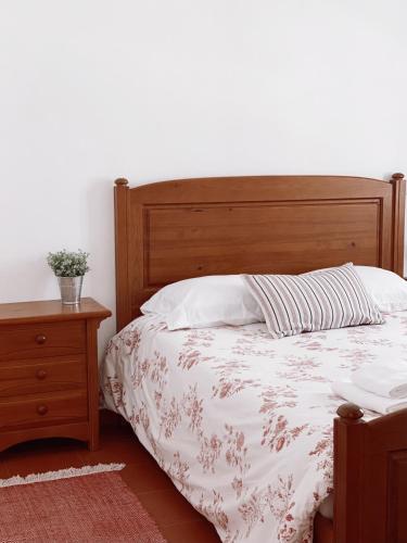 Schlafzimmer mit einem Bett mit einem Kopfteil aus Holz und einem Tisch in der Unterkunft Casa dos Pinheiros in São Pedro de Muel