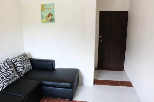a black leather couch sitting in front of a door at 2 Home in Chalong 