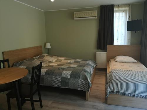 1 dormitorio con 2 camas, mesa, mesa y sillas en Atostogos Pervalkoje, en Pervalka