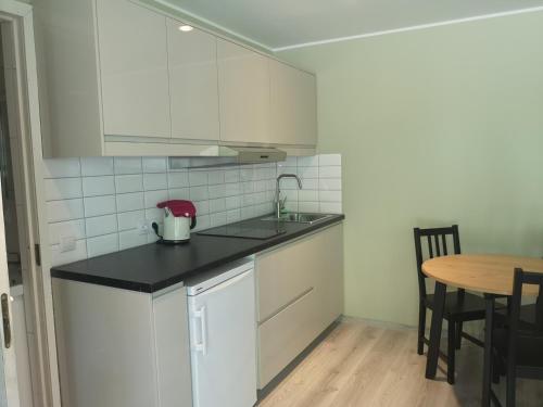 a white kitchen with a sink and a table at Atostogos Pervalkoje in Pervalka