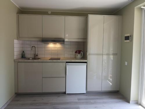 a kitchen with white cabinets and a refrigerator at Atostogos Pervalkoje in Pervalka