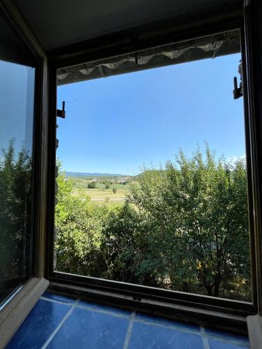 a window with a view of a field and trees at Le petit chalus in Forcalquier