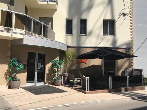 un café avec un parasol en face d'un bâtiment dans l'établissement Hotel San Marco, à Vasto