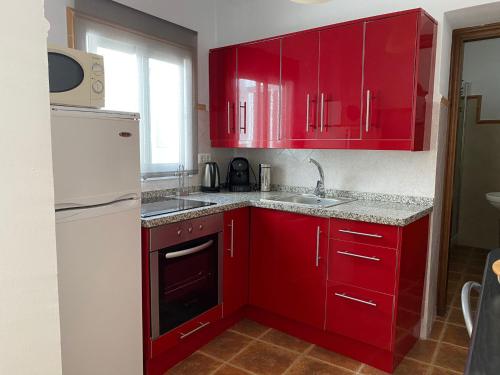 a red kitchen with a white refrigerator and red cabinets at Casa Carmen by VG in Maro