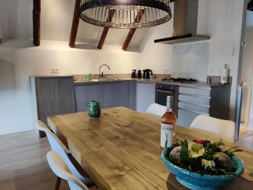 a kitchen with a wooden table with a bottle of wine at Appartement Badnieuweschans in Bad-Nieuweschans