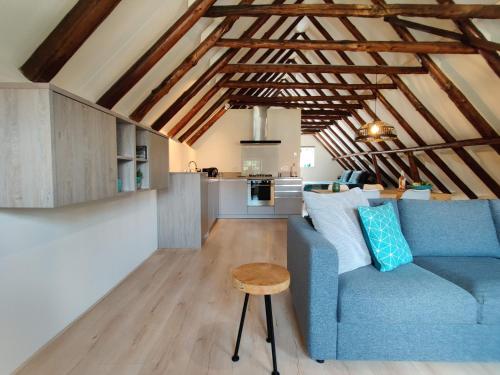 a living room with a blue couch and a table at Appartement Badnieuweschans in Bad-Nieuweschans