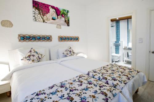 a white bedroom with a bed and a window at Lodos Hotel in Alacati
