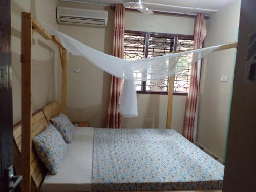 a bedroom with a bed with a canopy and a window at L&J Modern Backpackers Kinondoni in Dar es Salaam