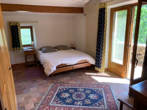 una camera con letto, finestra e tappeto di FONT NOUVELLE maison de charme Drôme Provençale, 6 ou 10 personnes avec piscine a Plaisians