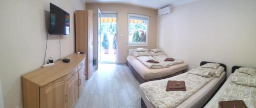 a room with two beds and a desk with a television at Relax Beach Apartman in Hajdúszoboszló