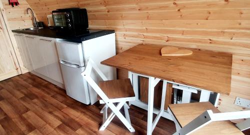 a small kitchen with a wooden table and a counter at The Pod at Hollingwell House - Glamping NC500 Edderton in Balblair