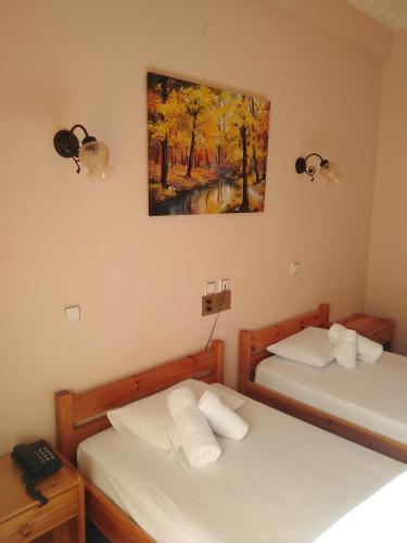 two beds in a room with a painting on the wall at Hotel Faraggi in Kleidonia