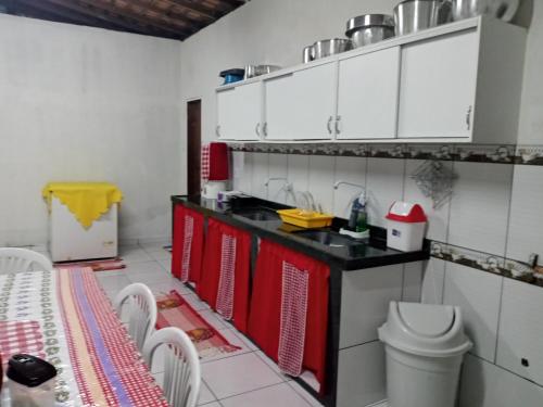 een keuken met rode en witte kasten en een tafel bij Salinas praia do atalaia in Salinópolis