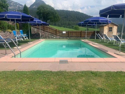 una piscina con sombrillas y sillas azules en App. Eichenheim en Fiè