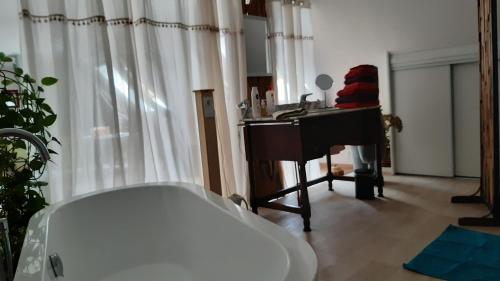 a bathroom with a bath tub and a piano at La martre in Saint-Sylvestre-de-Cormeilles