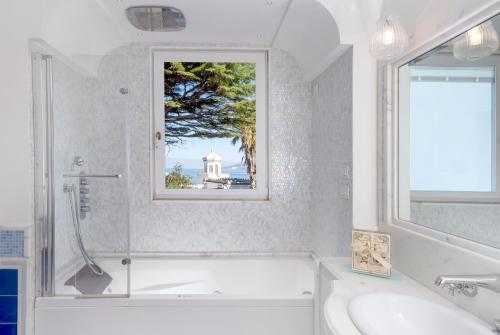 a bathroom with a bath tub, toilet, sink and window at Luxury Villa Excelsior Parco in Capri