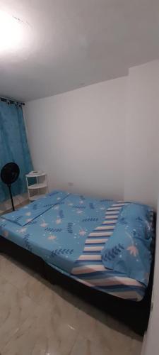a bedroom with a bed with a blue comforter at Hotel Alférez Real - Jamundí in Jamundí