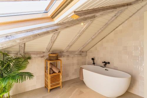 een badkamer met een groot wit bad en een dakraam bij Villa Horizonte Azul by Holiday Rental Madeira in Ponta do Sol