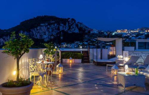a rooftop patio with tables and chairs at night at Luxury Villa Excelsior Parco in Capri