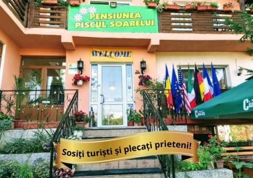 a sign in front of a restaurant with flags at Pensiunea Agroturistică Piscul Soarelui in Câmpulung