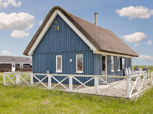 a blue house with a white fence in a field at 4 person holiday home in Harbo re in Harboør