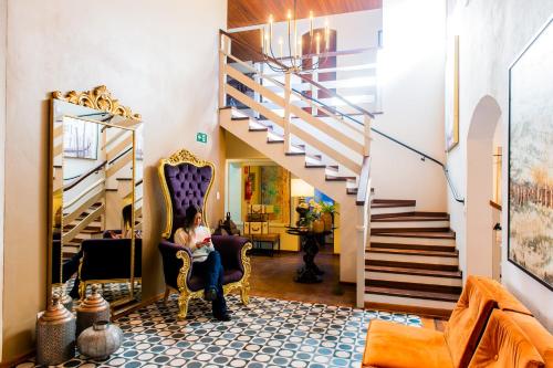 a woman sitting in a chair in a room with a staircase at Hotel Harmonia Monte Verde in Monte Verde