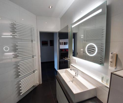 ein weißes Badezimmer mit einem Waschbecken und einem Spiegel in der Unterkunft Ihr Ticket ins Grüne - Topmoderne 5-Sterne-Ferienwohnung in Bad Kreuznach