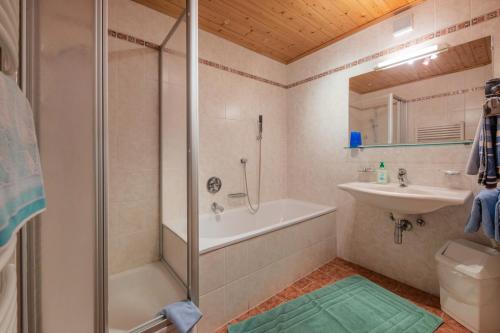 y baño con bañera de ducha y lavamanos. en Ferienwohnungen Mischbach, en Neustift im Stubaital